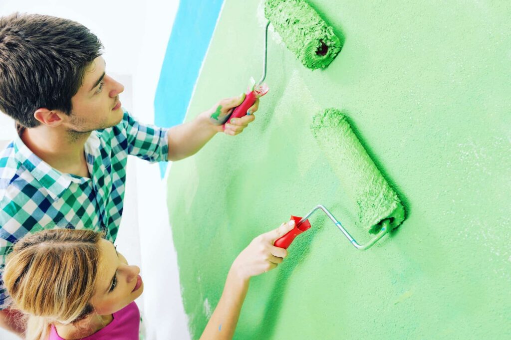 Malerbetrieb CasaColor: Ein Mann und eine Frau streichen eine Wand mit grüner Farbe.