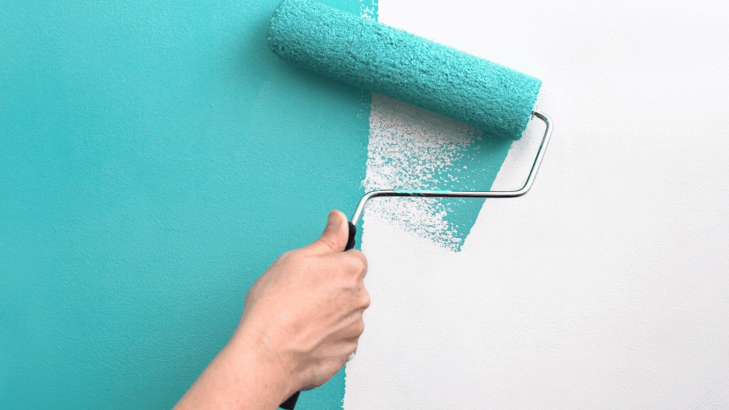 Malerbetrieb CasaColor: Eine Person streicht eine Wand mit einer Farbrolle in Türkis.