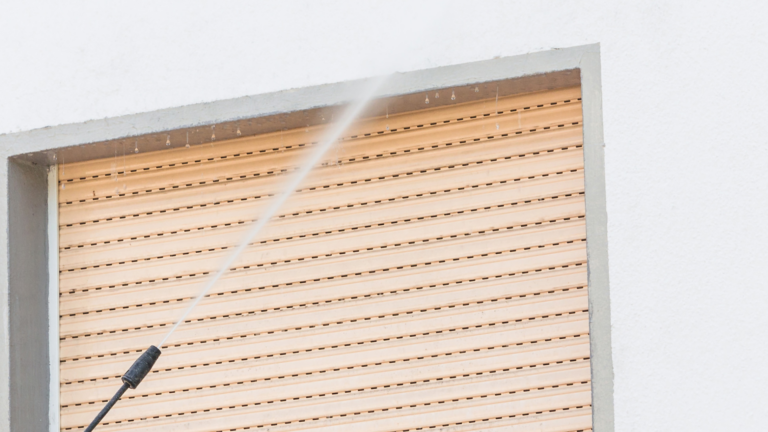 Fassade reinigen oder streichen? Eine Person reinigt die Fassade mit einem Hochdruckreiniger.