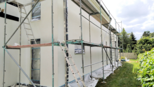 Hausfassade streichen: Ein frisch gestrichenes Haus mit einem Gerüst.
